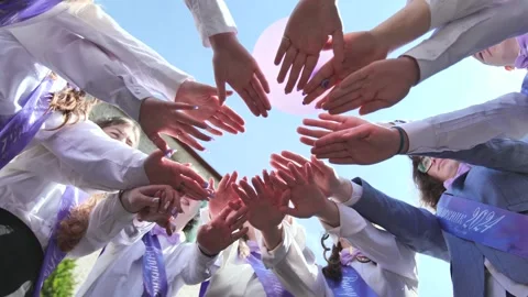 Cheerful students join hands in a circle, celebrating graduation and unity. The 스톡 동영상 316091733