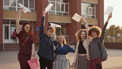 Cheerful students showing test result near school Stock Footage 258651289