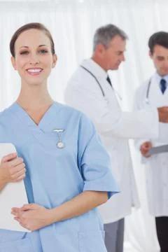 Cheerful surgeon posing while doctors talking on background Stock Photos