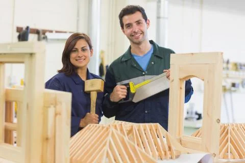 Cheerful trainee and instructor standing behind construction Stock Photos