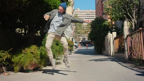 Cheerful trendy guy dances jumping around calm street enjoying happy life and Stock Footage 108436142