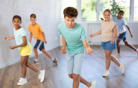Cheerful tween boy dancing with group of children in choreography class Stock Photos