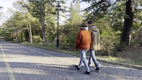 Cheerful two young spouses strolling on street in autumn park happy lovely Stock Photos