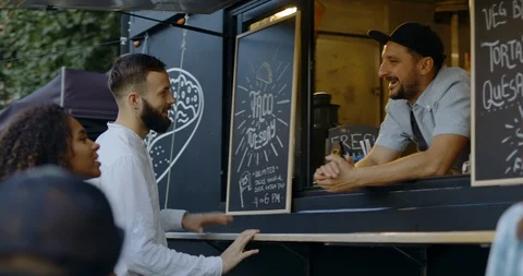 Cheerful waiter taking order from multi-racial customers at food truck Video stock 115627060