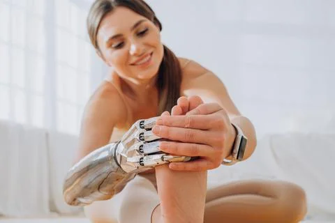 Cheerful woman with bionic arm does stretching exercises Stock Photos