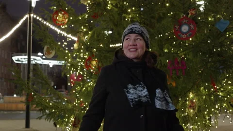 Cheerful woman singing while dancing under Christmas tree during night Stock Footage 302416822