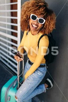 Cheerful woman traveller in sunglasses with a trolley bag Stock Photos