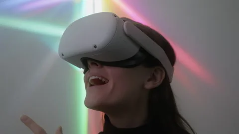 Cheerful woman using 3D virtual reality headset playing video game indoors Stock Footage 242275307