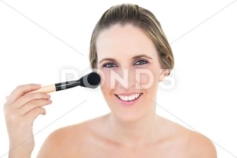 Cheerful woman using blusher brush Stock Photos