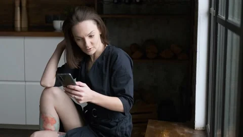 Cheerful woman using smartphone while sitting at home Stock Footage 144064420