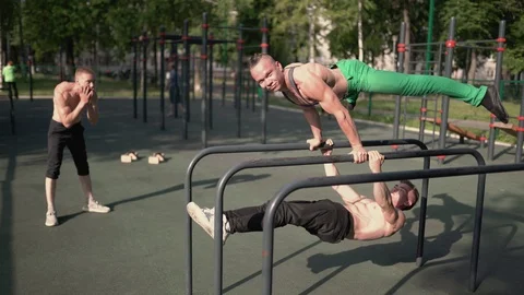 Cheerful young athletes at a workout on the parallel bars in the open air Stock Footage 92312545