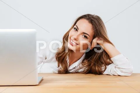 Cheerful young beautiful woman sitting at the desk with laptop Stock Photos