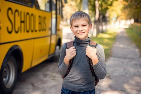Cheerful young boy with a backpack returning home by school bus Stock Photos