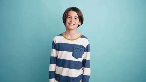 Cheerful young boy smiling against a blue background Stock Footage 339039525