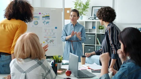 Cheerful young businesswoman giving good news to colleagues making report with Stock Footage 148337306