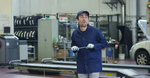 Cheerful young car mechanic in a car service, having fun and dancing with wrench Stock Footage