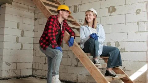 Cheerful young construction workers talking in half-built house Stock Photos