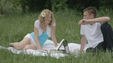 Cheerful young couple discussing something with opened book and laptop Stock-Footage 7766970