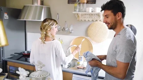 Cheerful young couple having fun together while washing dishes in kitchen Stock Footage 74729367