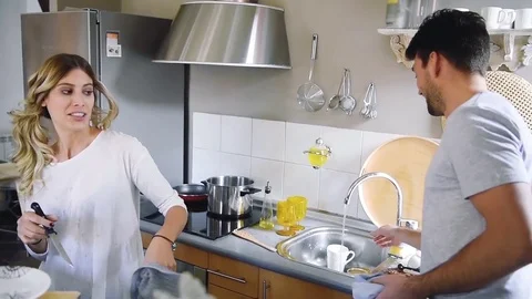 Cheerful young couple having fun together while washing dishes in kitchen. Stock Footage 74729427