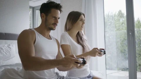 Cheerful young couple having fun and playing videogames together in the bdero Stock Footage 79796531
