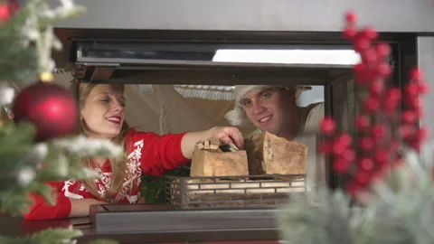 Cheerful young couple is loading firewood to light a fireplace on Christmas Eve Stock Footage 221152542