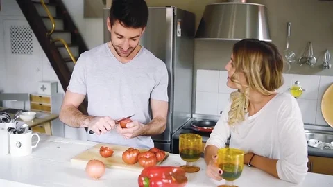 Cheerful young couple sitting at kitchen together and cooking dinner Stock Footage 74728528