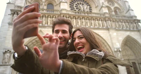 Cheerful young couple taking selfies on a cellphone in front of Notre Dame Vídeo Stock 200813149