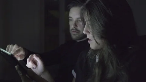 Cheerful young couple using tablet pc at home Stock Footage 100547168