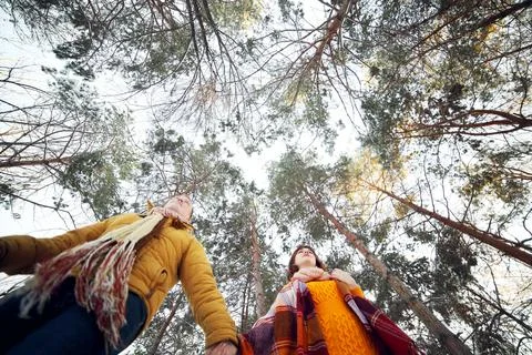 Cheerful young couple walking in the winter forest, low angle Stock Photos