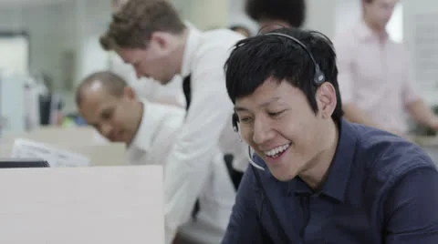 Cheerful young customer service operator, at work in a busy call center Stock Footage 25760150