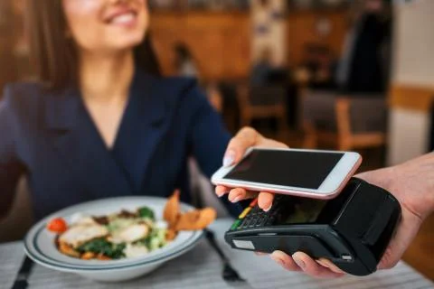 Cheerful young customer sit at table and look at waitress. She smile. Model hold Stockfoto's