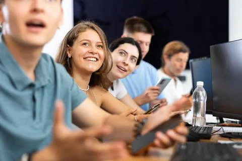 Cheerful young female student using mobile phone in computer workshop Stock Photos