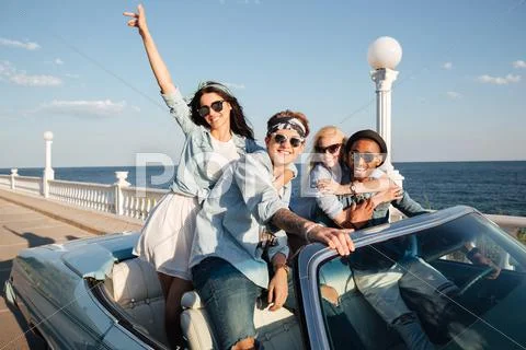 Cheerful young friends driving car outdoors Stock Photos
