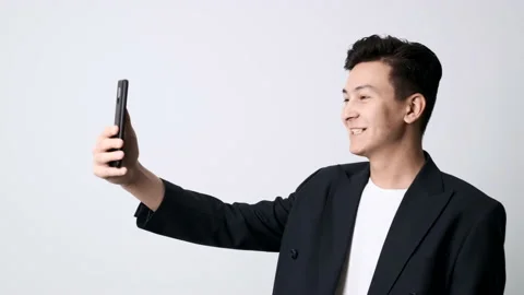 A cheerful young guy in a jacket and with a mobile phone in his hands Stockbeeldmateriaal 162192058