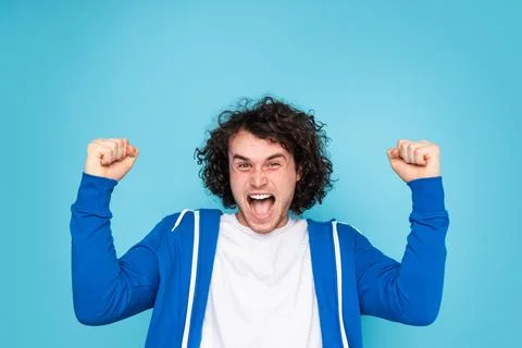 Cheerful young guy shouting expressively while celebrating victory Stock Photos