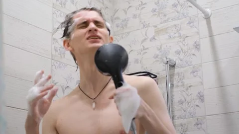 Cheerful young guy singing in the shower while bathing 库存影片 283401828