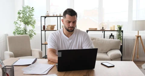 Cheerful young guy using laptop working at home doing distant work Stock Footage 150020463