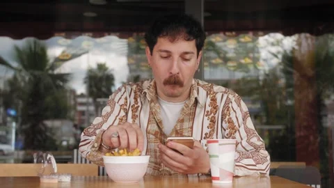 Cheerful young hispanic man sitting in cafe street and using smartphone Stock Footage 270957834