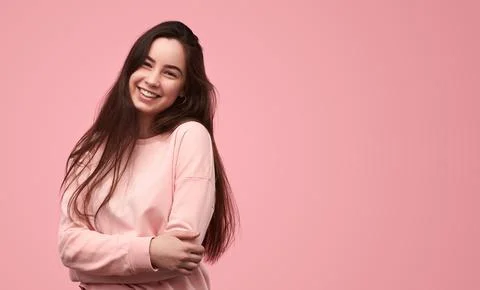 Cheerful young lady smiling while standing in pink studio Stock Photos