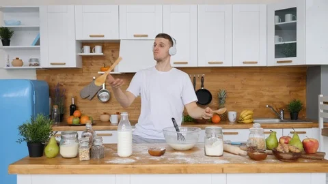Cheerful Young Man Dancing In Kitchen Listening To Music In Headphones. Видео 105297772