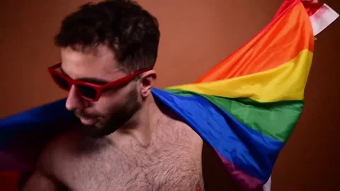 Cheerful young man dancing with a rainbow lgbt pride flag Video stock 329930603