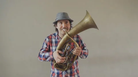 Cheerful young man with a funny mustache and a hat playing on the big tuba. Stock Footage