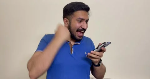 Cheerful young man reading a good news on his mobile phone and got excited after Stock Footage 241446296