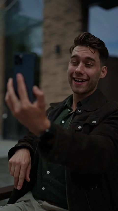 Cheerful young man taking selfie with smartphone while making peace sign Stock Footage 297630449