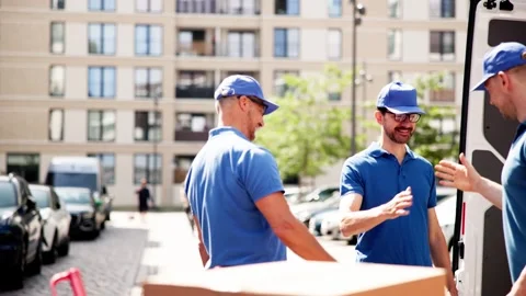 Cheerful young man in uniform stands proudly in front of moving van Stock Footage 278697223