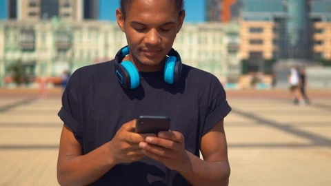 Cheerful young man using app on smartphone walking on the street Stock Footage 112928609
