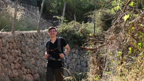 Cheerful young man walking calmly on a rocky path exploring Stock Footage 294520073