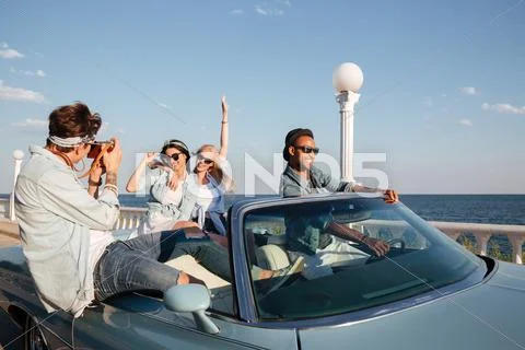 Cheerful young people driving a car and talking photos Stock Photos