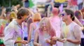 Cheerful young people throwing colorful powder in air, dancing at festival 4k or 4k+ Resolution